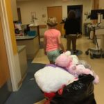 Hadley pulling a wagon of large stuffed animals in a hospital hallway.