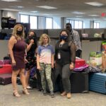 Hadley standing amongst women with donated luggage behind them