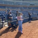 Attendees standing at baseball game.