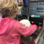 Hadley scanning stuffed animal at a self-scan machine.