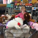 Hadley standing next to shopping cart full of stuffed animals