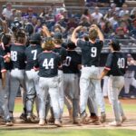 A baseball team gathers to celebrate in front of an onlooking crows in the stands at the Duel on the Diamond event