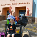 Haley sits ouside the front of the Maricopa County Animal Care & Control building beside a cart of donated supplies for animals