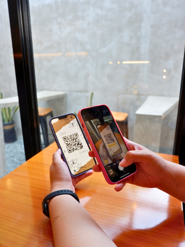 Someone scanning a QR code on one smartphone with another